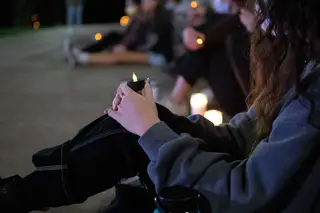 Members of the crowd hold battery powered candles to show their solidarity with survivors at SU.