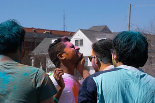 Attendees smear pink and orange powder on each other’s faces to celebrate Holi.